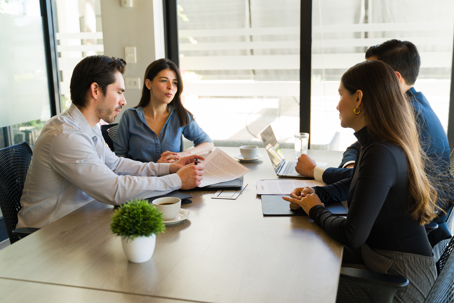 Profile view of a young Caucasian couple getting a mortgage and signing a contract in a meeting room
